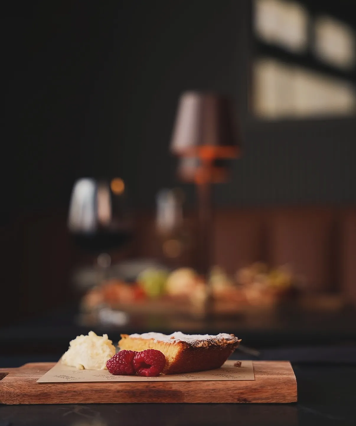 A slice of cake with raspberries and cream on a wooden board