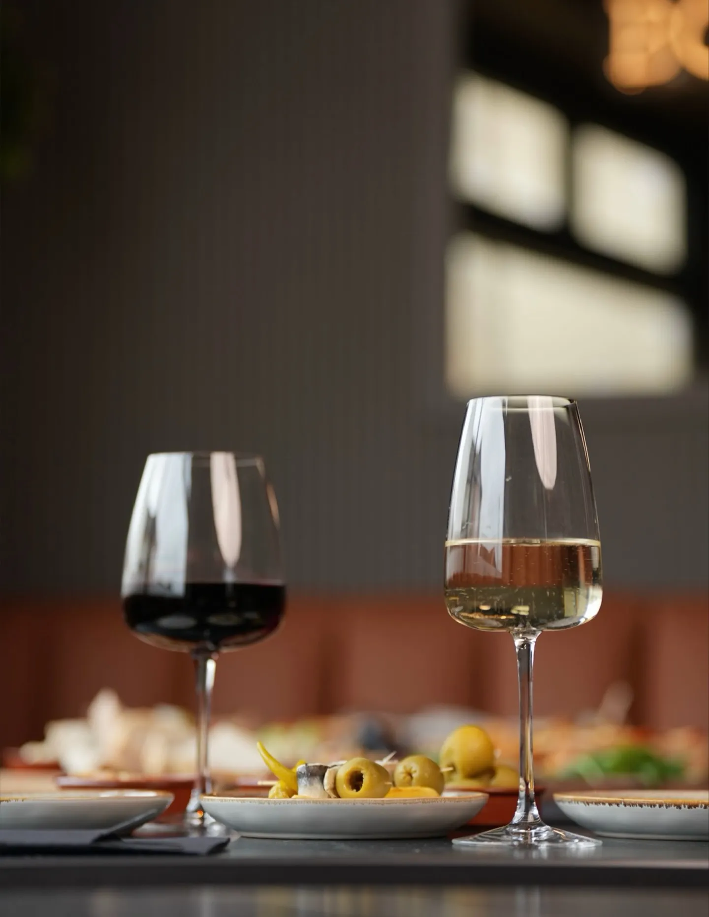 Glasses of red and white wine with bar snacks at a window table